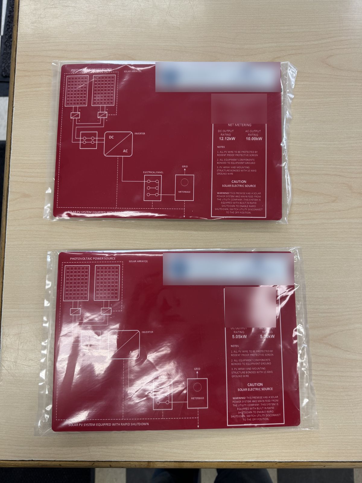 Two bagged red lamacoid single-line diagram plates for solar installs, white text on red
