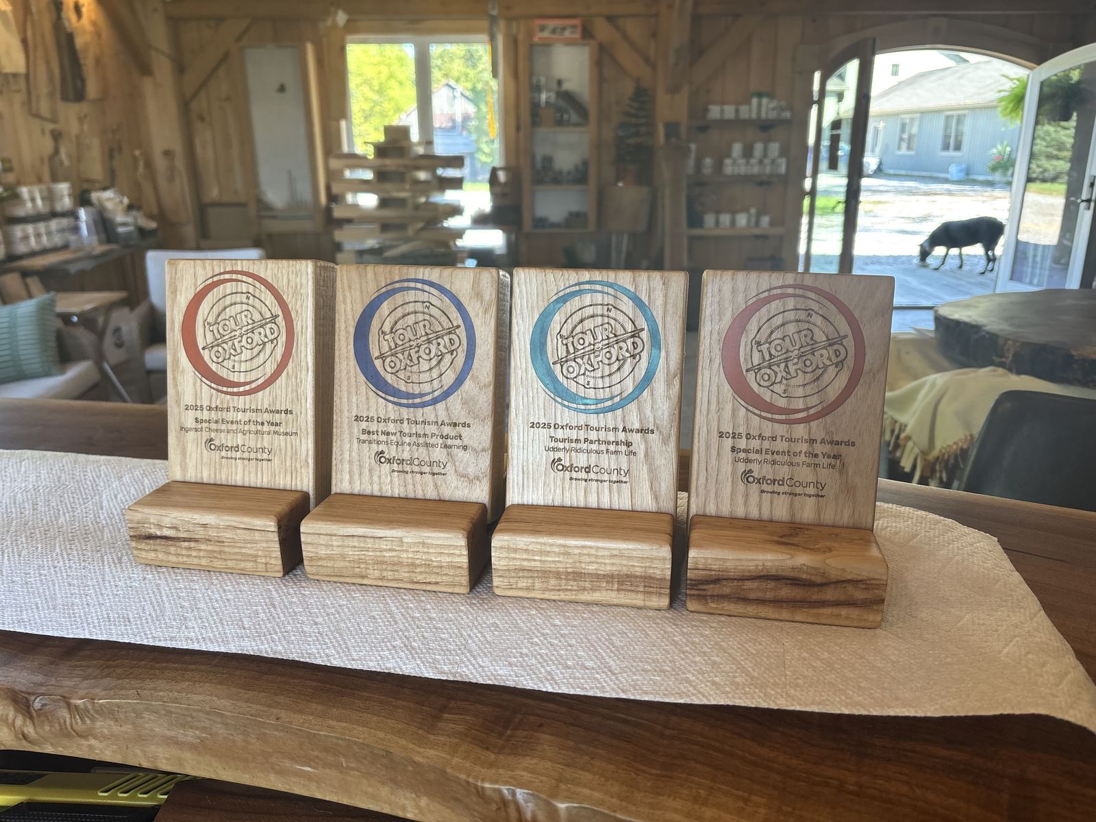 Four engraved wood award plaques with coloured logos, standing on wooden bases