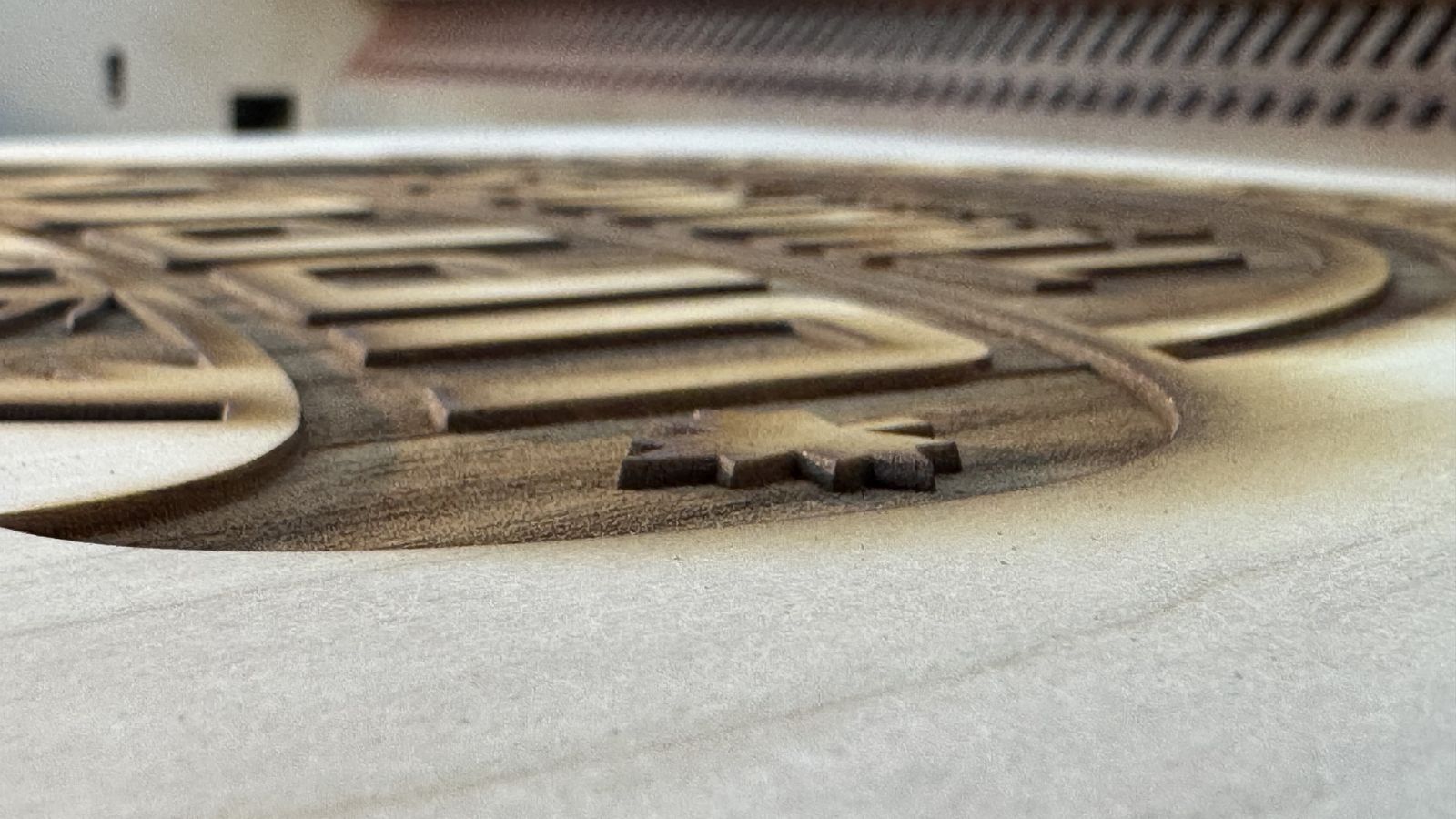 Close-up of deep relief laser engraving in wood, showing the carved depth
